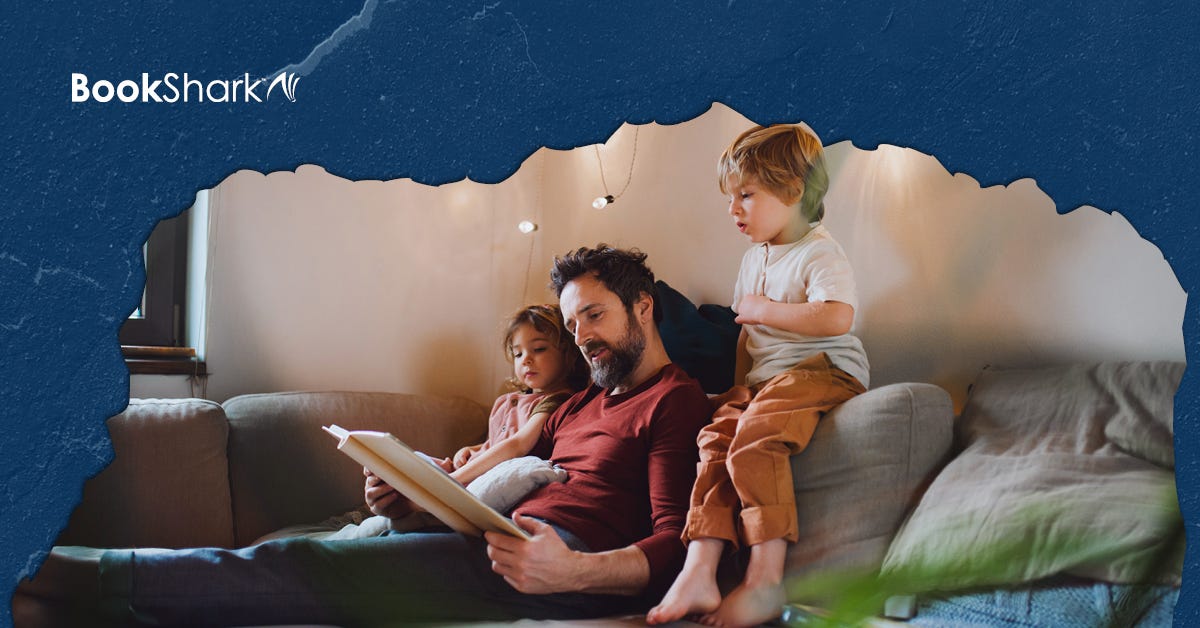 a dad and two kids sit/stand on a couch, reading a book