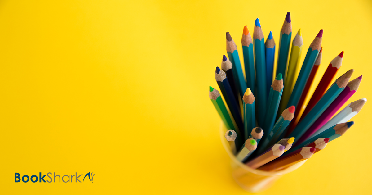 sharpened colored pencils stand in a cup against a bright yellow background