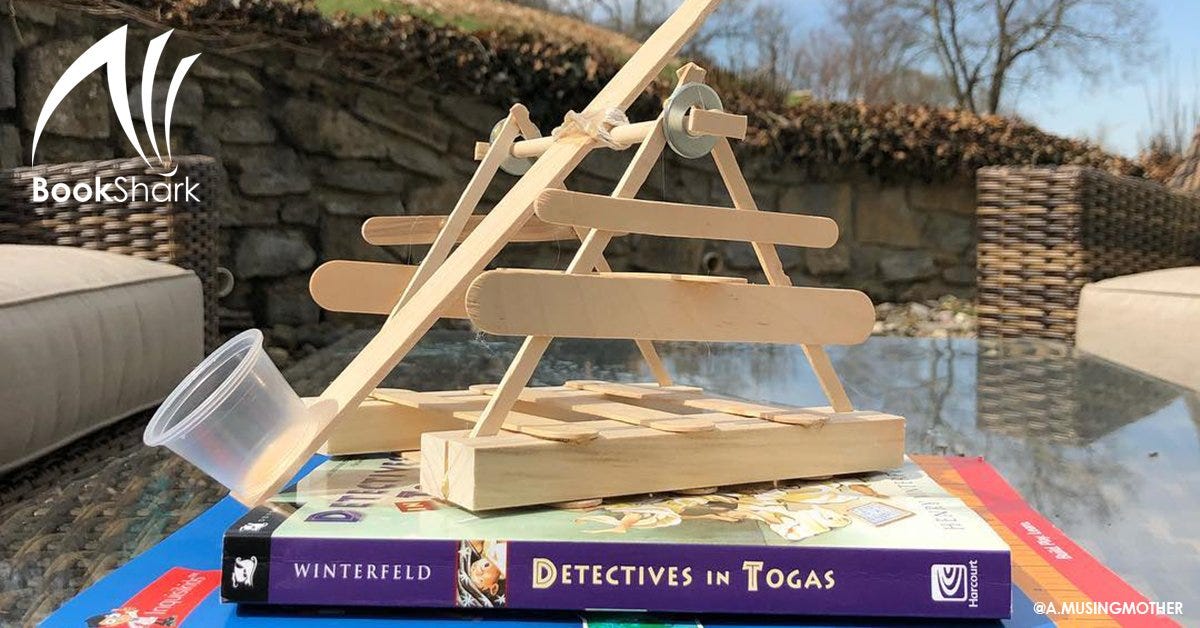 a catapult made from craft sticks sits atop a stack of BookShark Readers