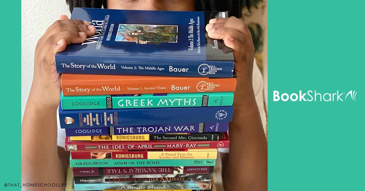 a boy holds a stack of middle school books