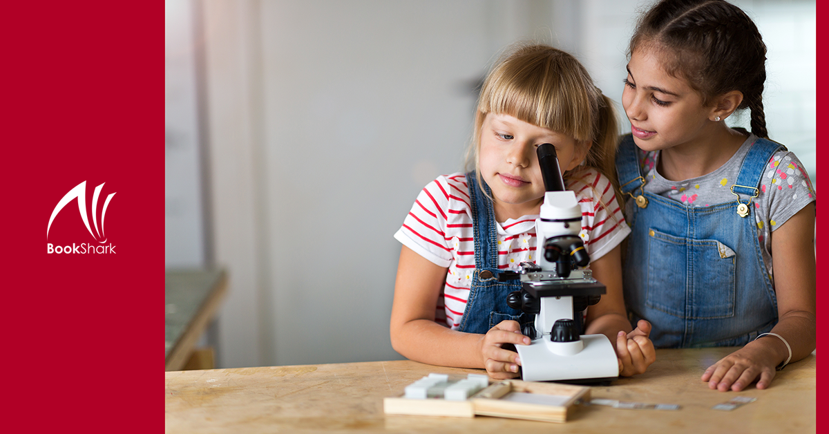 one girl looks through a microscope while another girl stands nearby, waiting