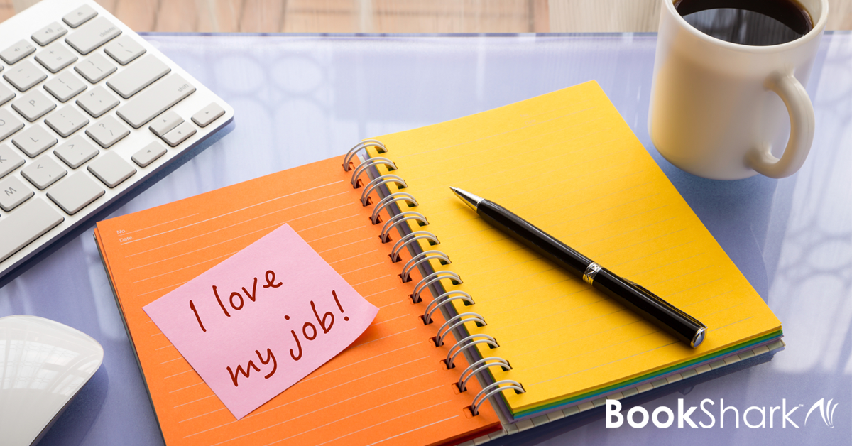 a spiral bound notebook sits open with a sticky note saying "I love my job"